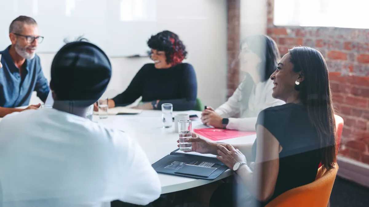 A group of people sit around a table in an office.