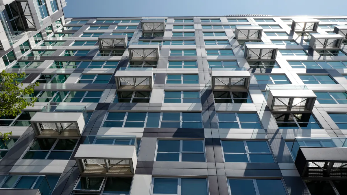 Modern multi-story apartment building viewed from below.