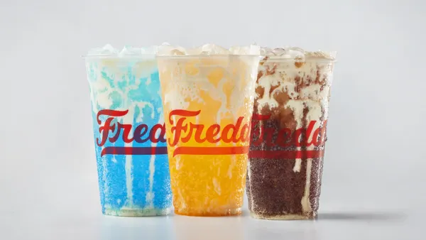 Three colorful sodas with white custard cream dribbling down the inside of the cups.