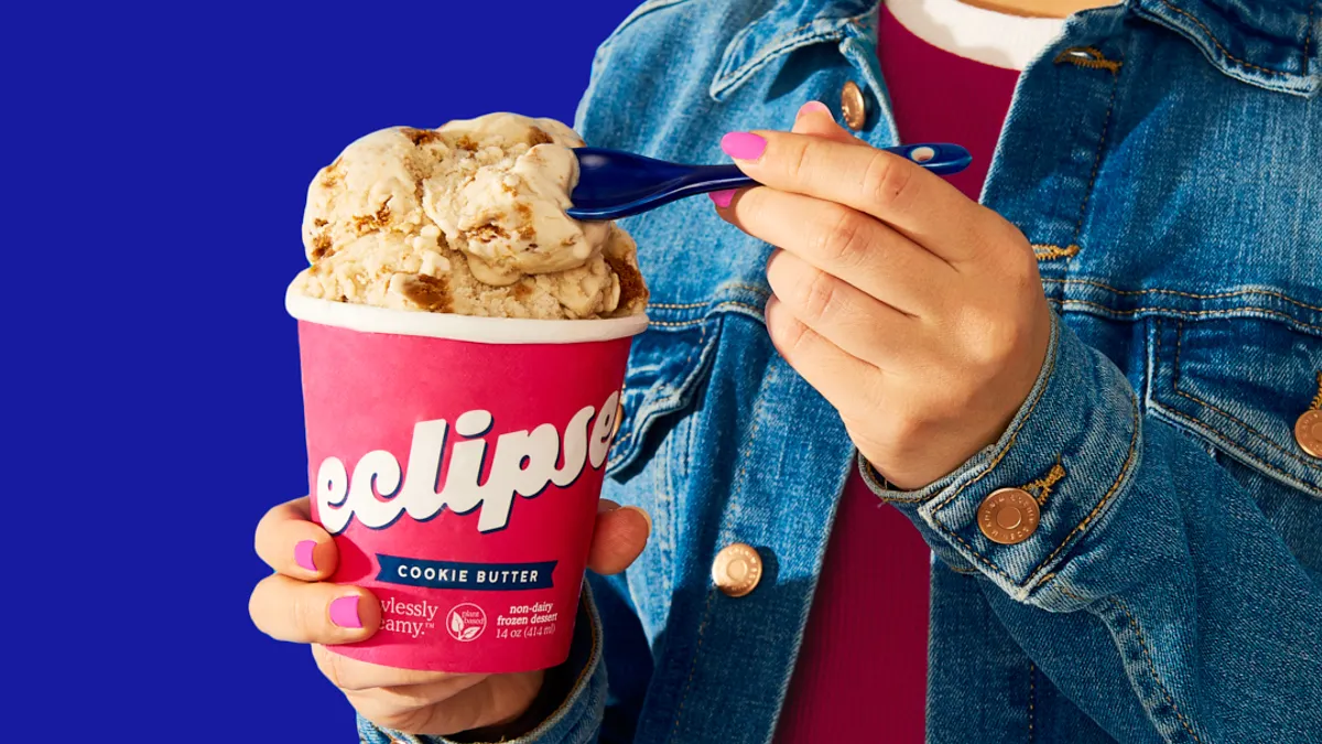 A person holds a pint of Eclipse Cookie Butter ice cream