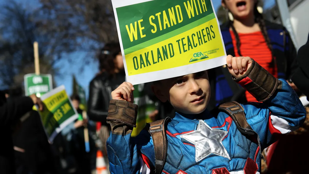 A child holds a sign that reads "We Stand With Oakland Teachers" during a 2019 protest outside of Manzanita Community School.