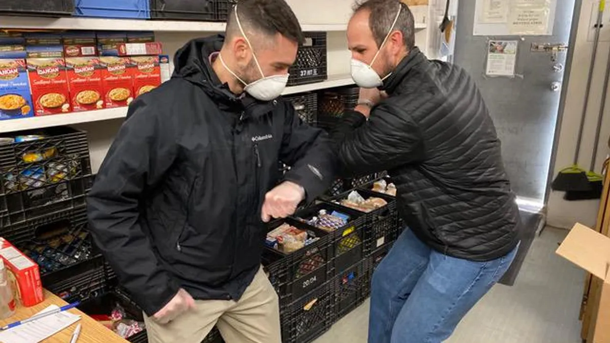 Two men wearing masks and bumping elbows in lieu of a handshake. Taken on March 18, 2020.