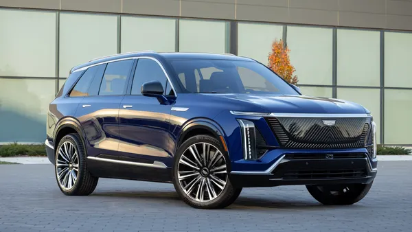 A front 3/4 view of a 2026 Cadillac VISTIQ in Opulent Blue Metallic parked in front of a building.