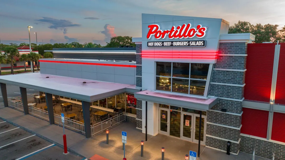 An evening shot of a building with white and red coloring and signage that says "Portillo's."