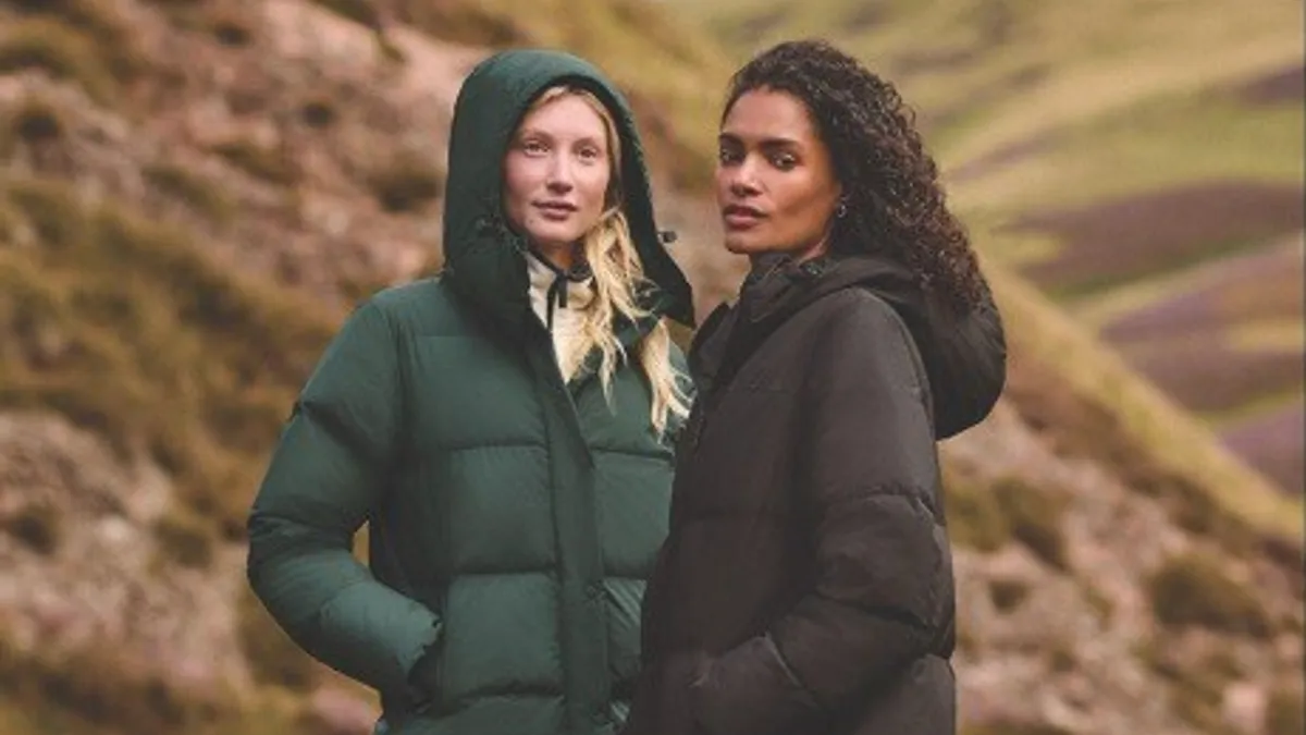 Two people wearing coats stand in a rocky landscape.