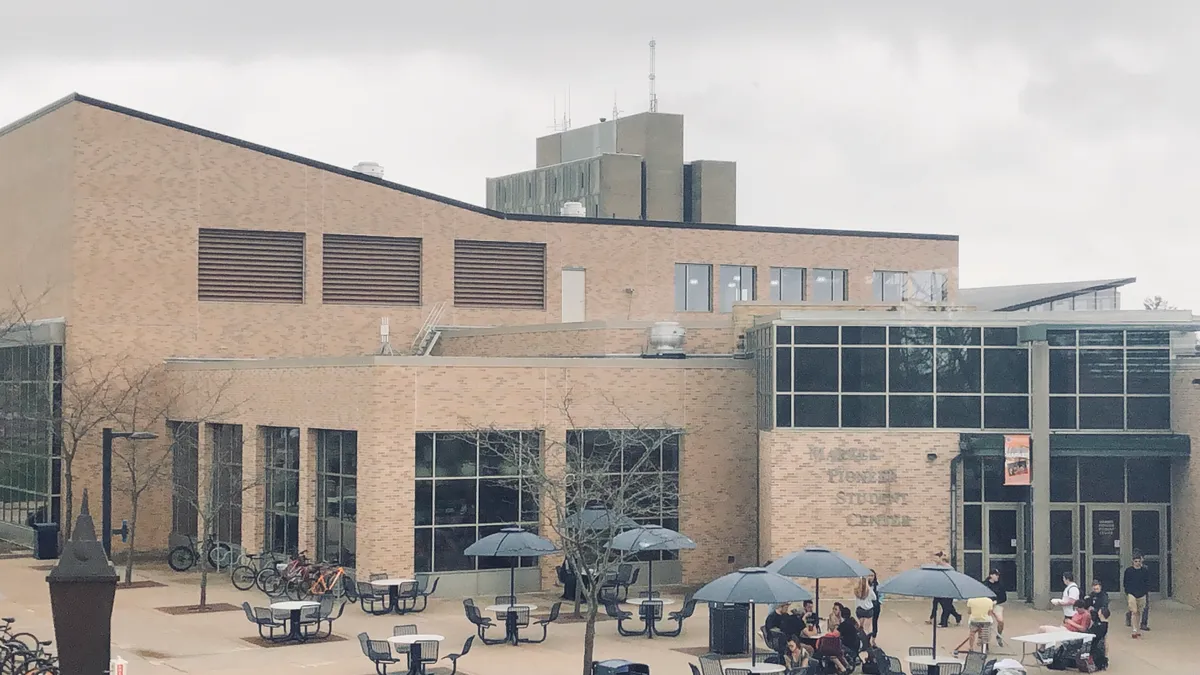 A brick college student center with a patio and outdoor seating