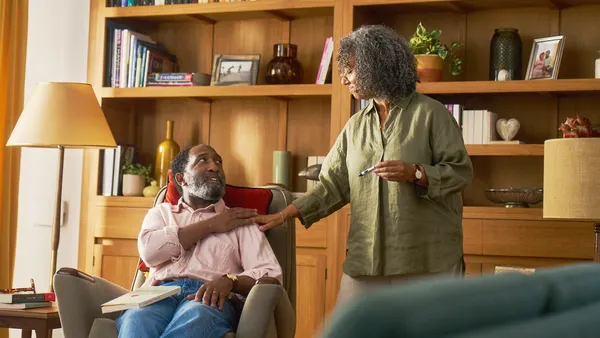 A person seated in an armchair looks up at another in this still image taken from a video commercial.