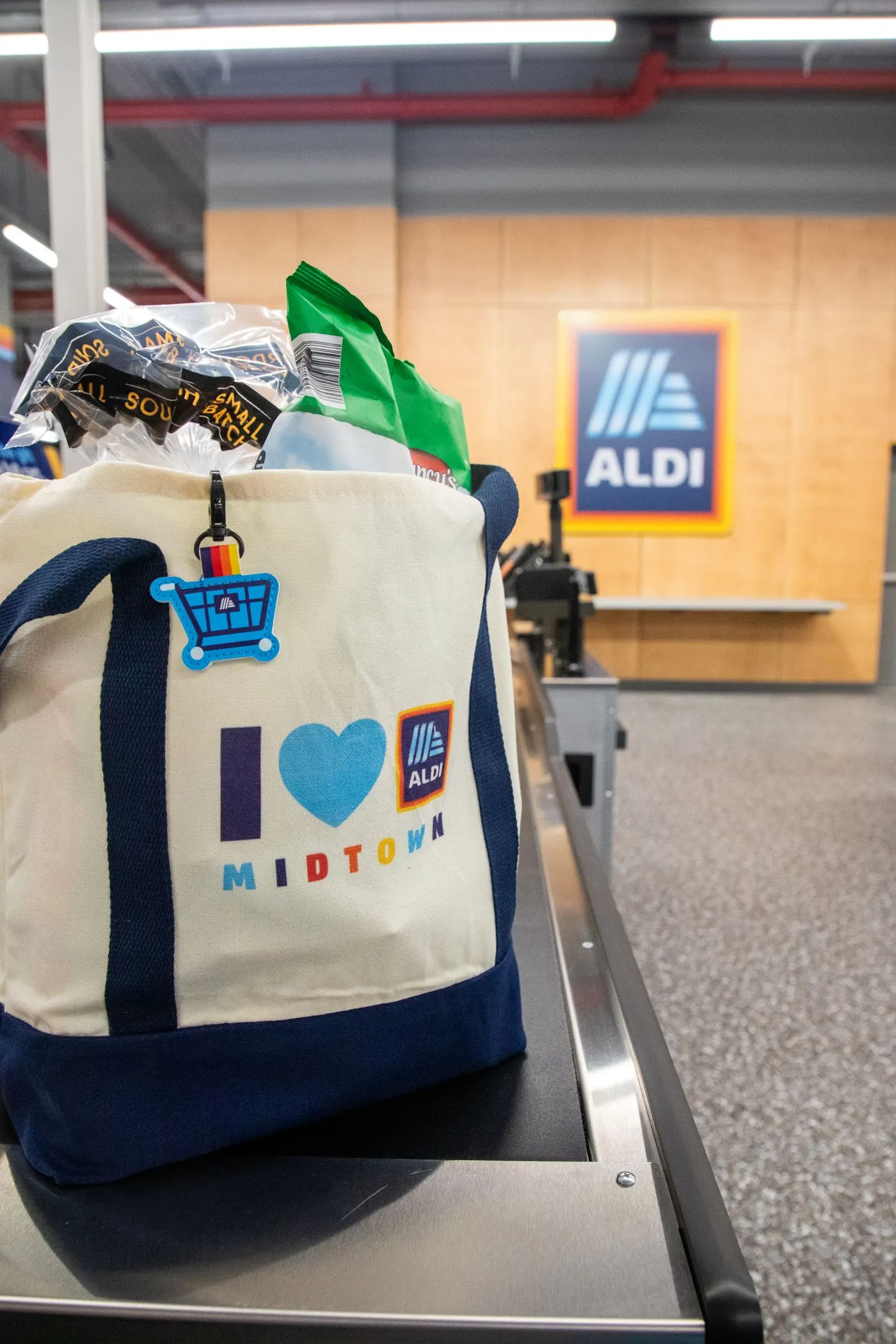 An Aldi tote bag sitting on a grocery checkout conveyor belt