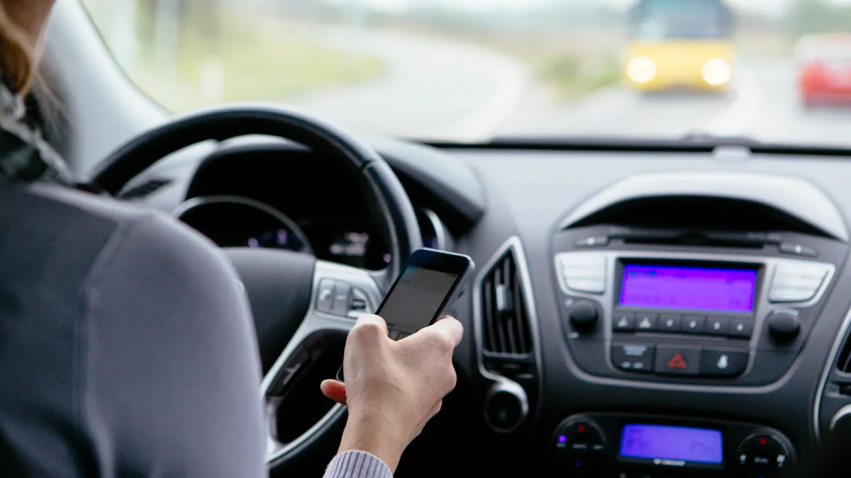 A woman looks at her smartphone and while driving.