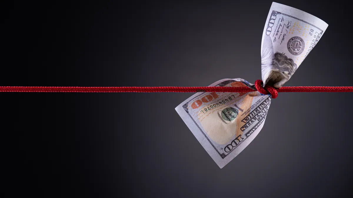 American dollar tied up in red rope knot