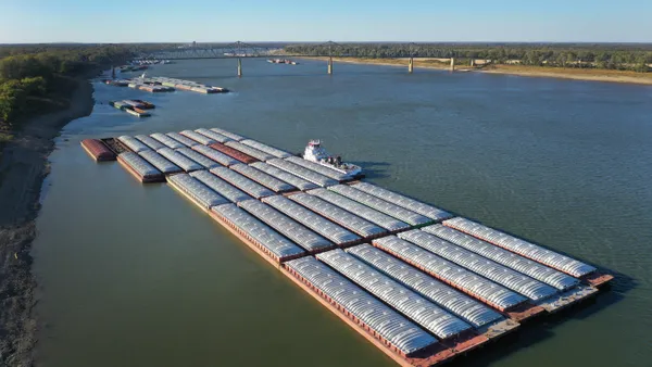 an aerial shot of the Ohio River shows barges tied together along the bank.