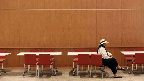 A person sits among a row of chairs.