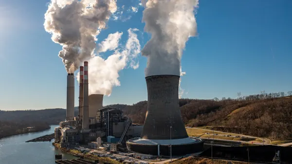 Smoke pours from smokestacks by a river.