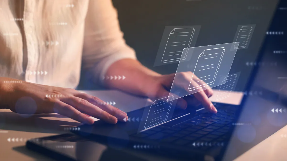 Close up of a person's hands on a laptop overlaid with translucent images of arrows and documents