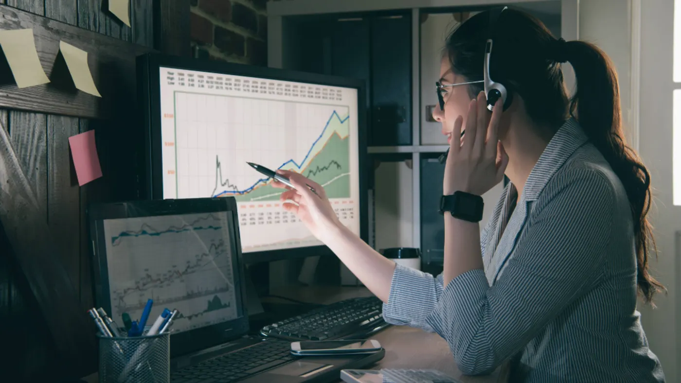 person at desk with graphs on monitors