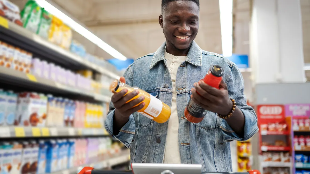 A person comparing two different drinks in a grocery store.