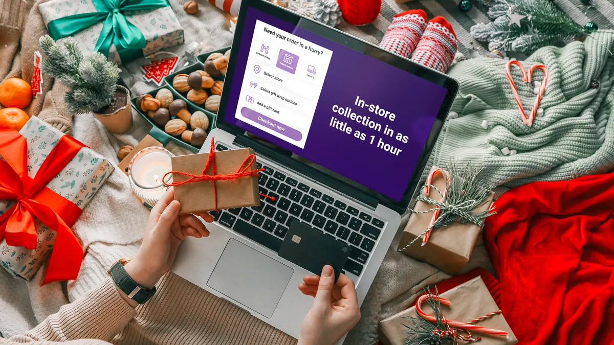 Woman holding a credit card and a gift box against the background of Christmas decor and gifts