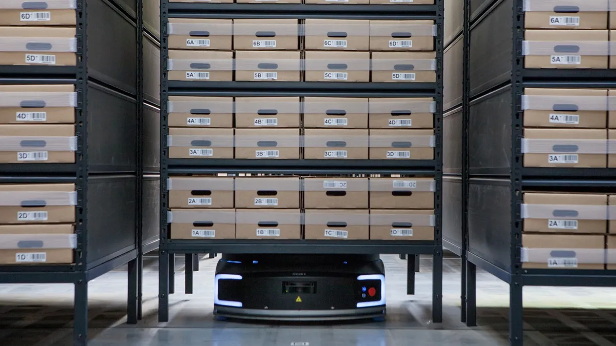 Three shelves with boxes of files on them, and a robot underneath one shelf