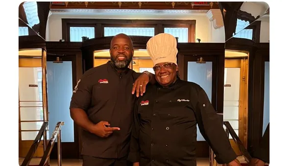 Two chefs standing in front of their restaurant.