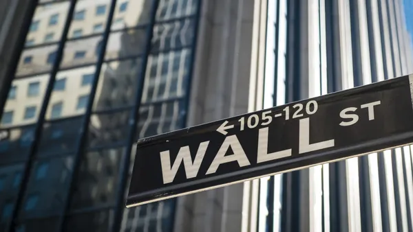 Close up of Wall Street sign, with tall buildings in the background.