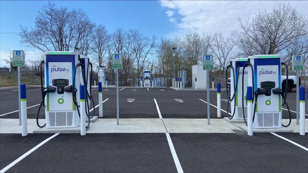 A photo of a parking lot with a number of EV chargers set up alongside the parking spaces.
