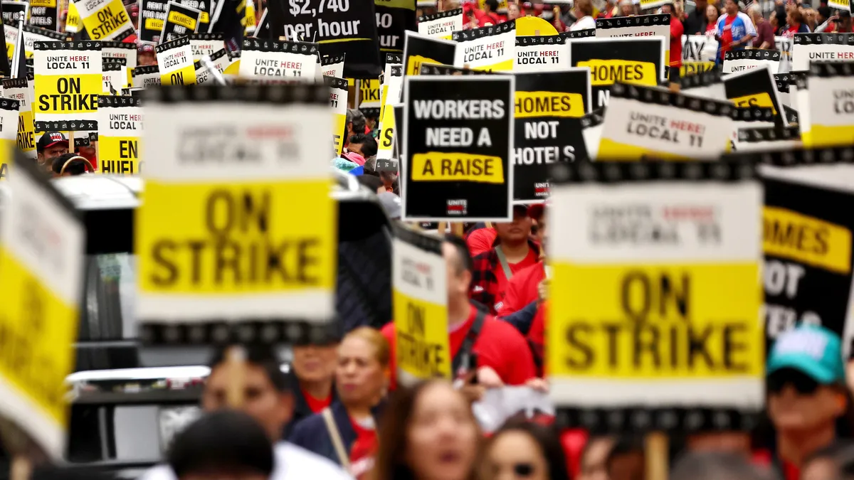 Hotel workers hotel picket signs reading "ON STRIKE."