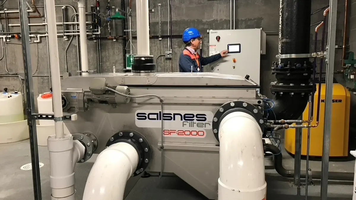 A person working on a system of pipes and a large white box.
