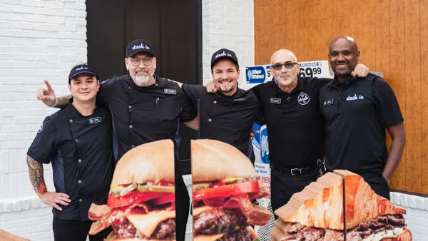 A photo of several people in black shirts standing in a line inside a store with icons of food in front of them.