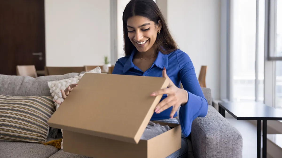 Person opening cardboard box, smiling