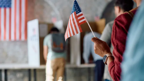 Close up of African American voter with national flag in waiting line during US elections.