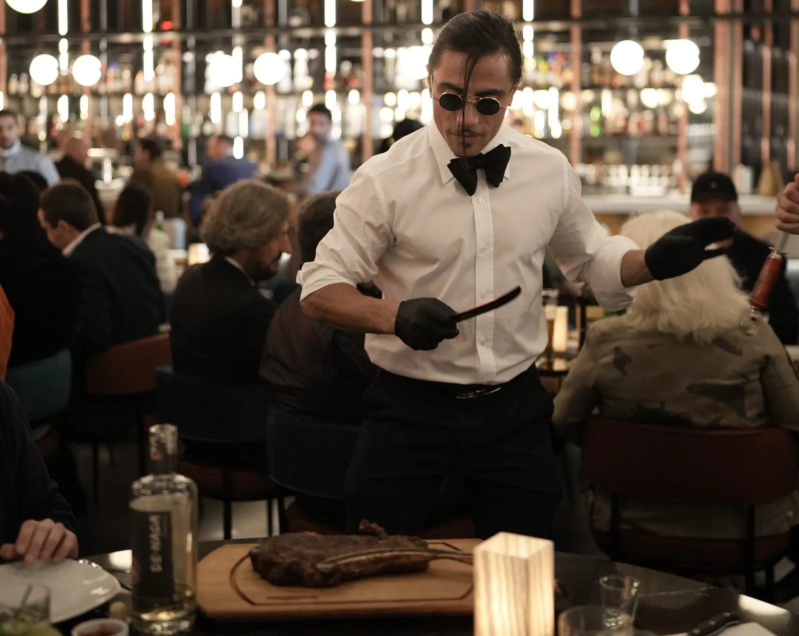 Salt Bae cuts meat at a table side in Nusr-Et Steakhouse