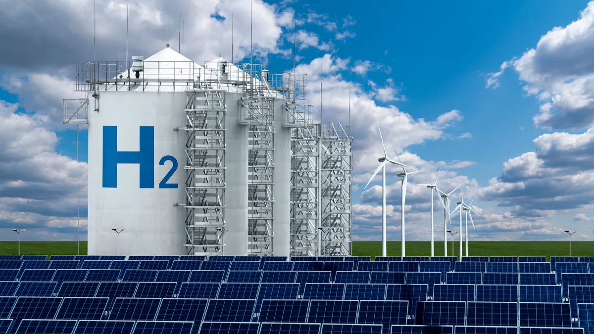 A hydrogen tank with solar panels in the foreground and wind turbines in the background.