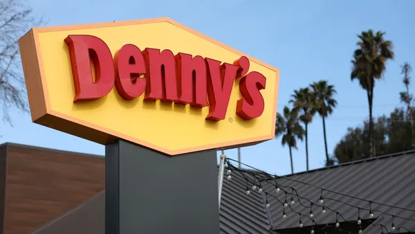 A photograph of a yellow sign with Denny's in red.