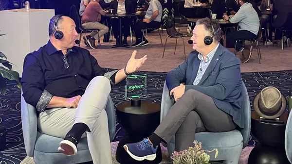 two sitting men with headphones talk to each other