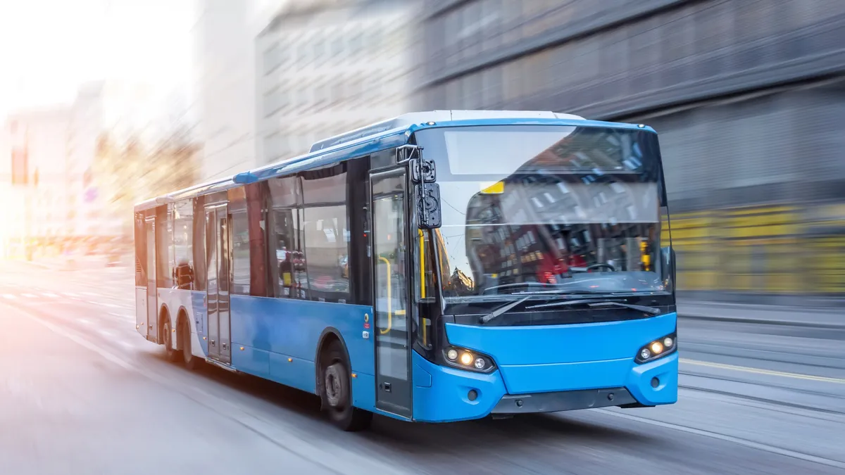 A city blue bus moving on the road in the early morning.