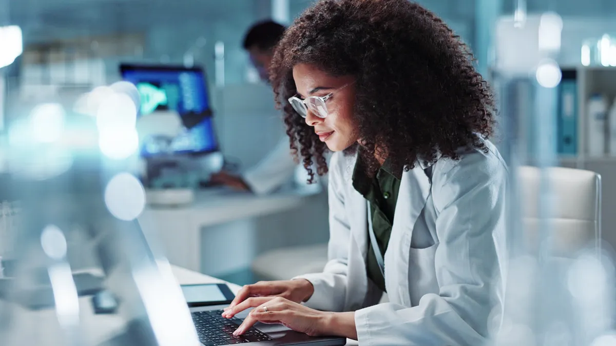 A scientist in a lab on their laptop