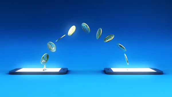 Creative image with coins jumping from one phone to another.