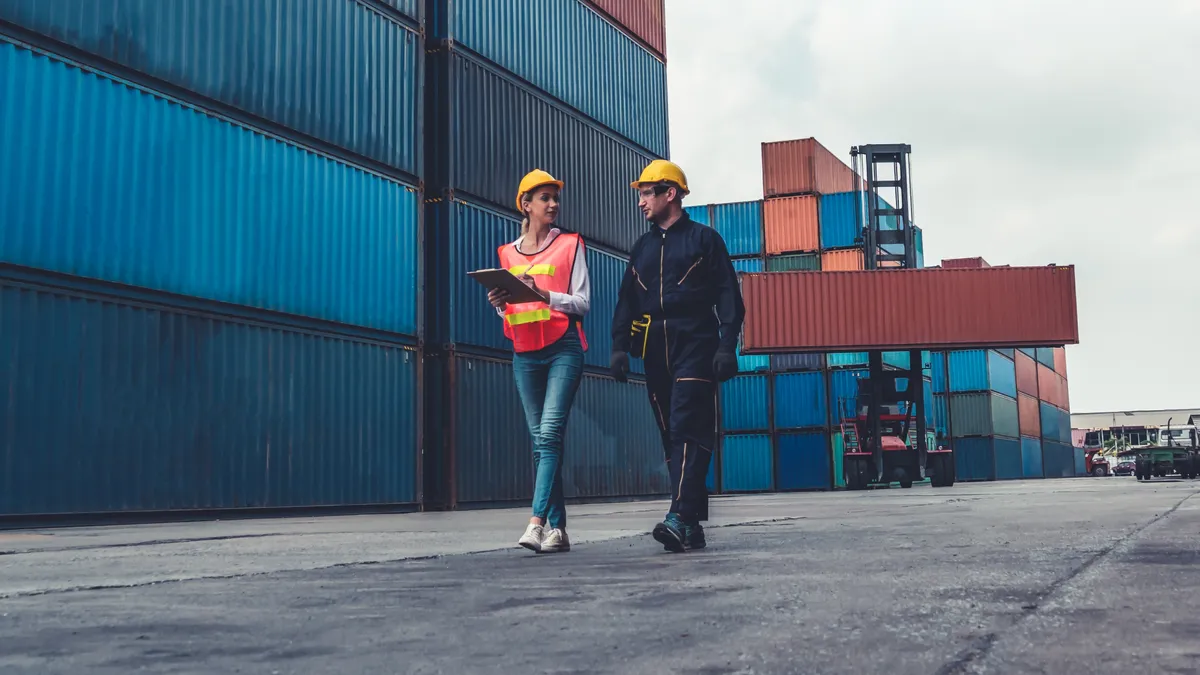 Two people walking between storage containers