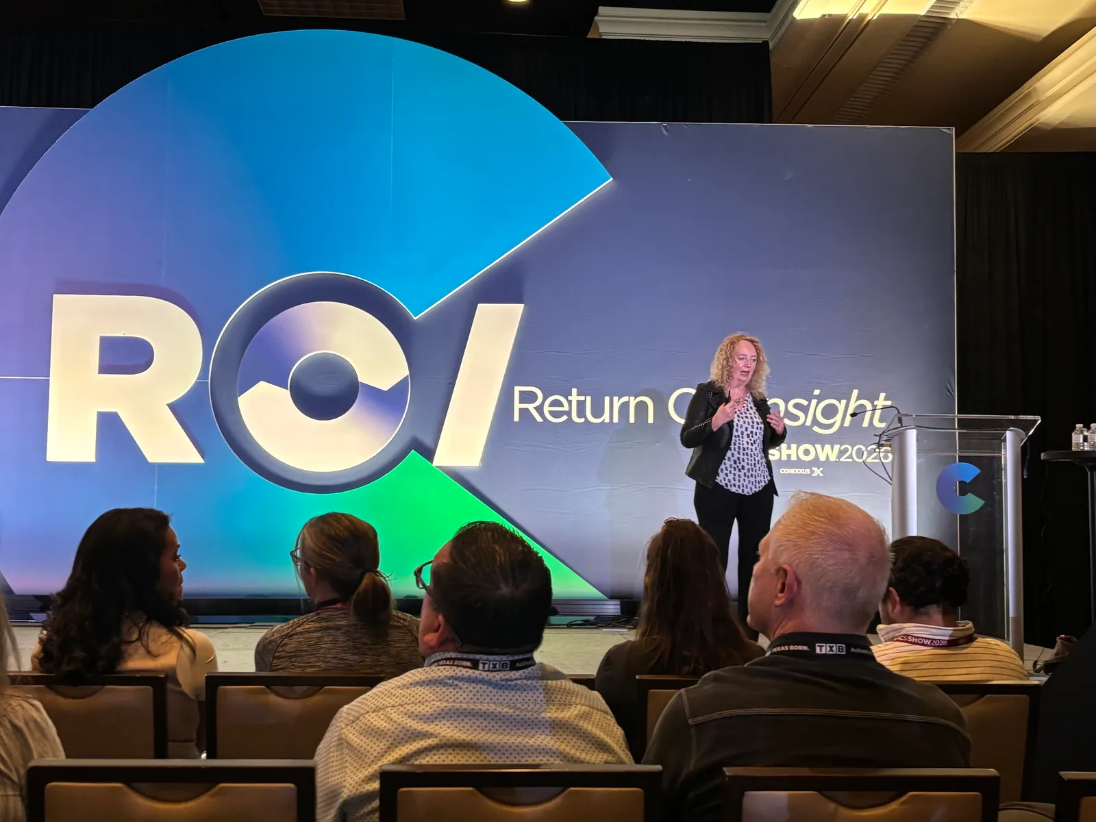 A person speaks to a crowd from a stage. The background says "POI Return On Insight. NACS Show 2026."