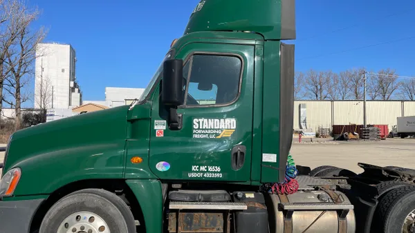 A green truck labeled Standard Forwarding Freight, LLC is parked on a lot.