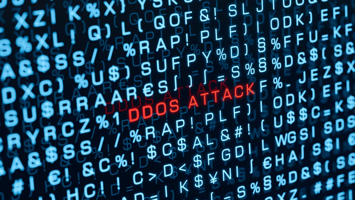 The words ddos attack are spelled out in red on a computer screen amid random blue text.