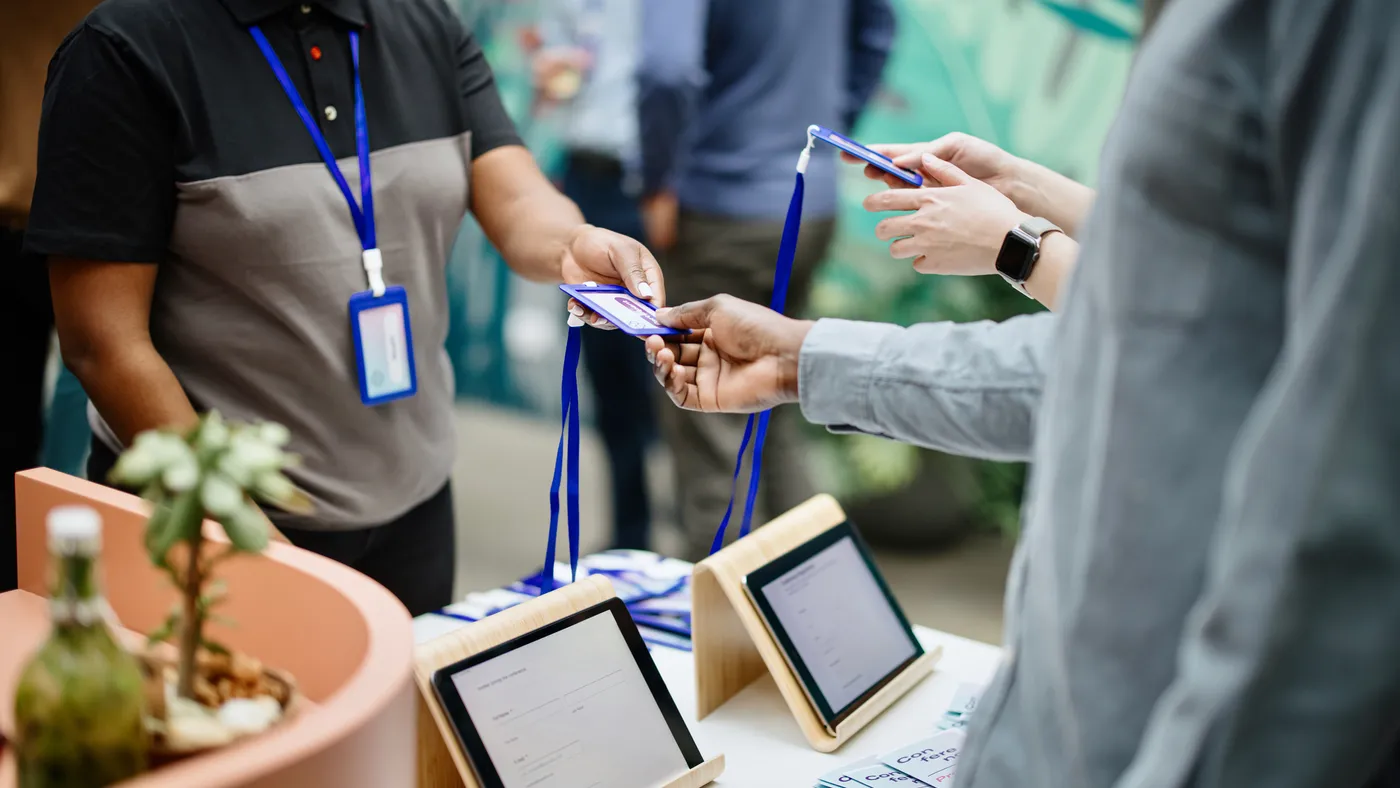 Conference staff handing out accreditation badges to attendees