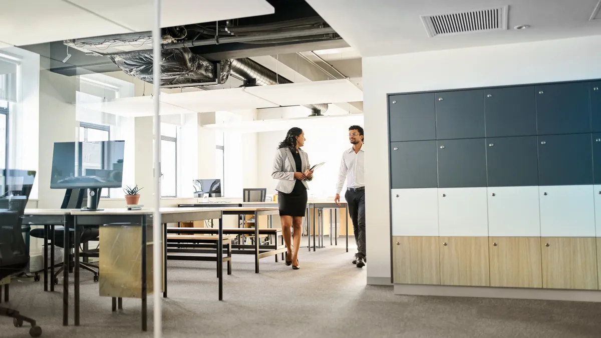 An office real estate agent walks through an empty office with a tenant.