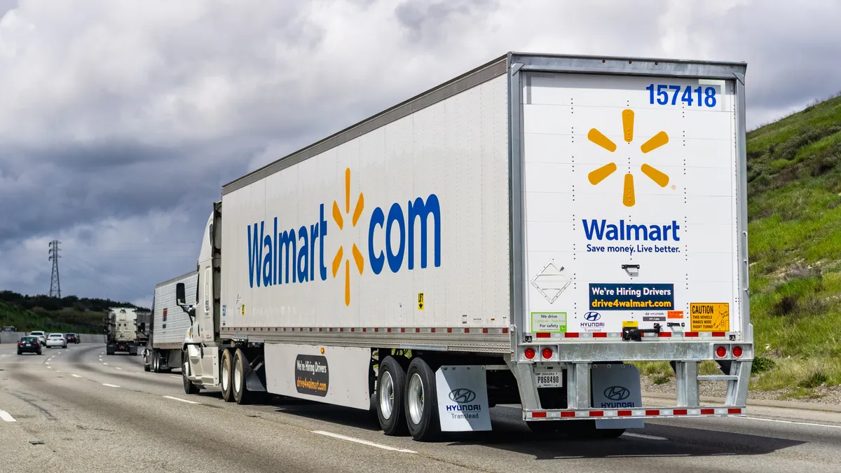 A Walmart truck emblazoned with "drive4Walmart" recruitment advertisements drives on a road.