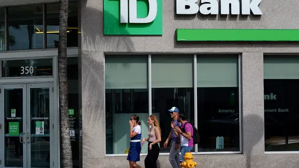 Four people walk by a TD bank branch location