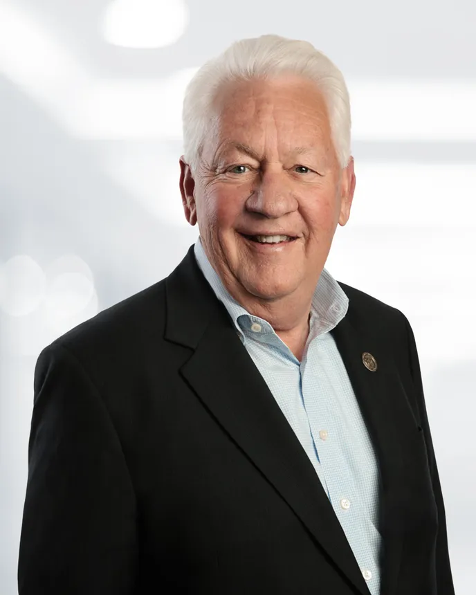 Headshot of a man with white hair in a dark suit