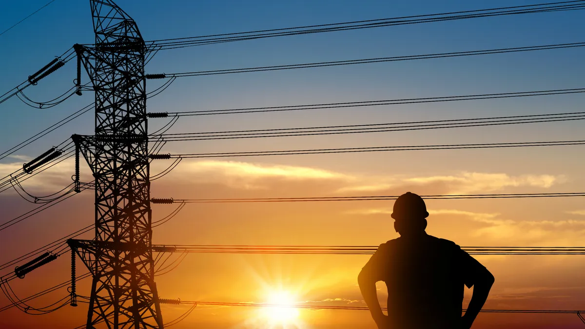 Electrician worker and electricity power lines over sunset sky.