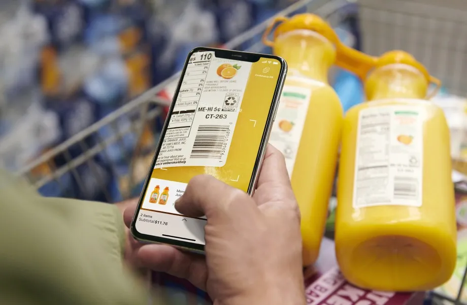 A hand using a phone to scan the back of an orange juice container