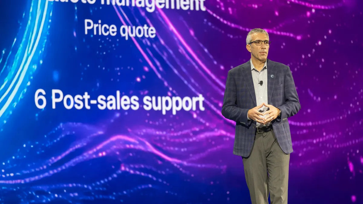 A technology executive stand onstage presenting a conference keynote presentation.