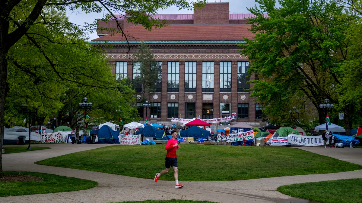 A person runs past a pro-Palestinian encampment on the University of Michigan's campus.